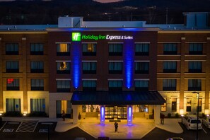 Edificio de Holiday Inn Express & Suites con fachada de ladrillo, señalización iluminada y una zona de entrada cubierta.