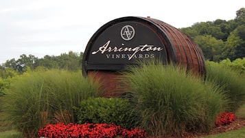 Un panneau en forme de tonneau sur lequel on peut lire « Arrington Vineyards », le tout entouré de verdure et de fleurs rouges.