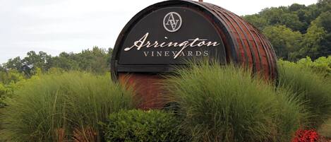 Un panneau en forme de tonneau sur lequel on peut lire « Arrington Vineyards », le tout entouré de verdure et de fleurs rouges.