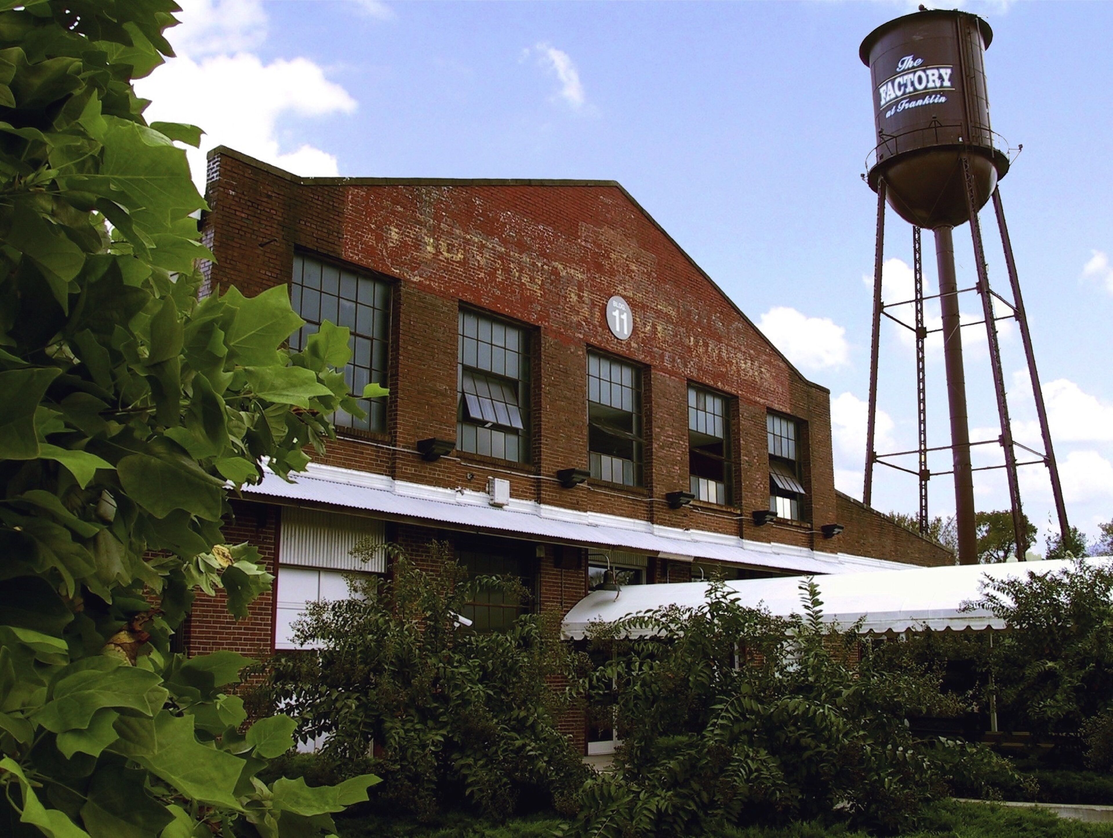 A historic brick building with a water tower labeled "The Factory at Franklin".