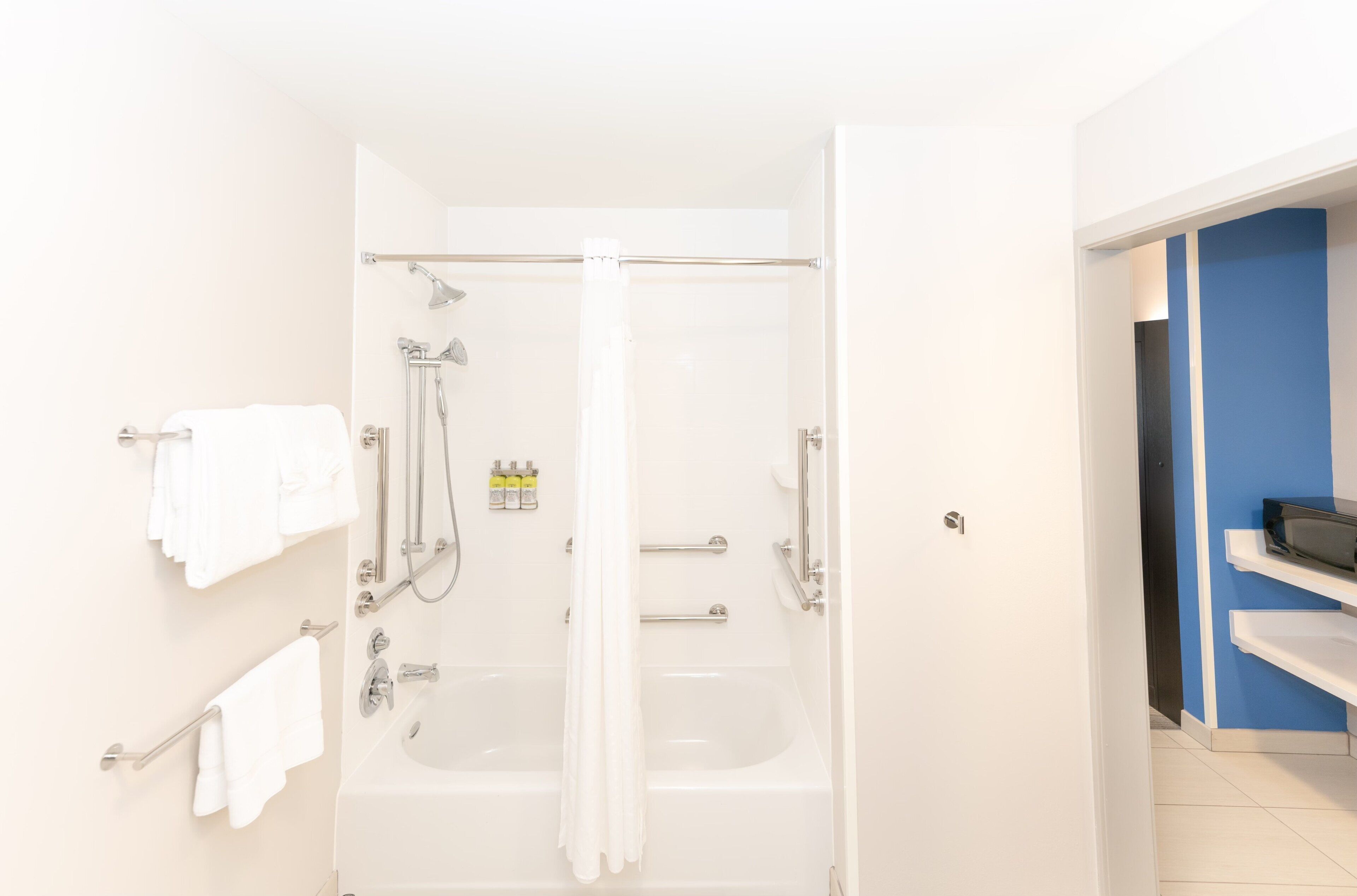 Une salle de bain avec une baignoire, une douche et des toilettes. Des serviettes sont accrochées au mur.
