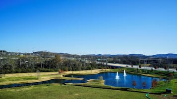 Un parque con un estanque, fuentes y un puente al fondo.