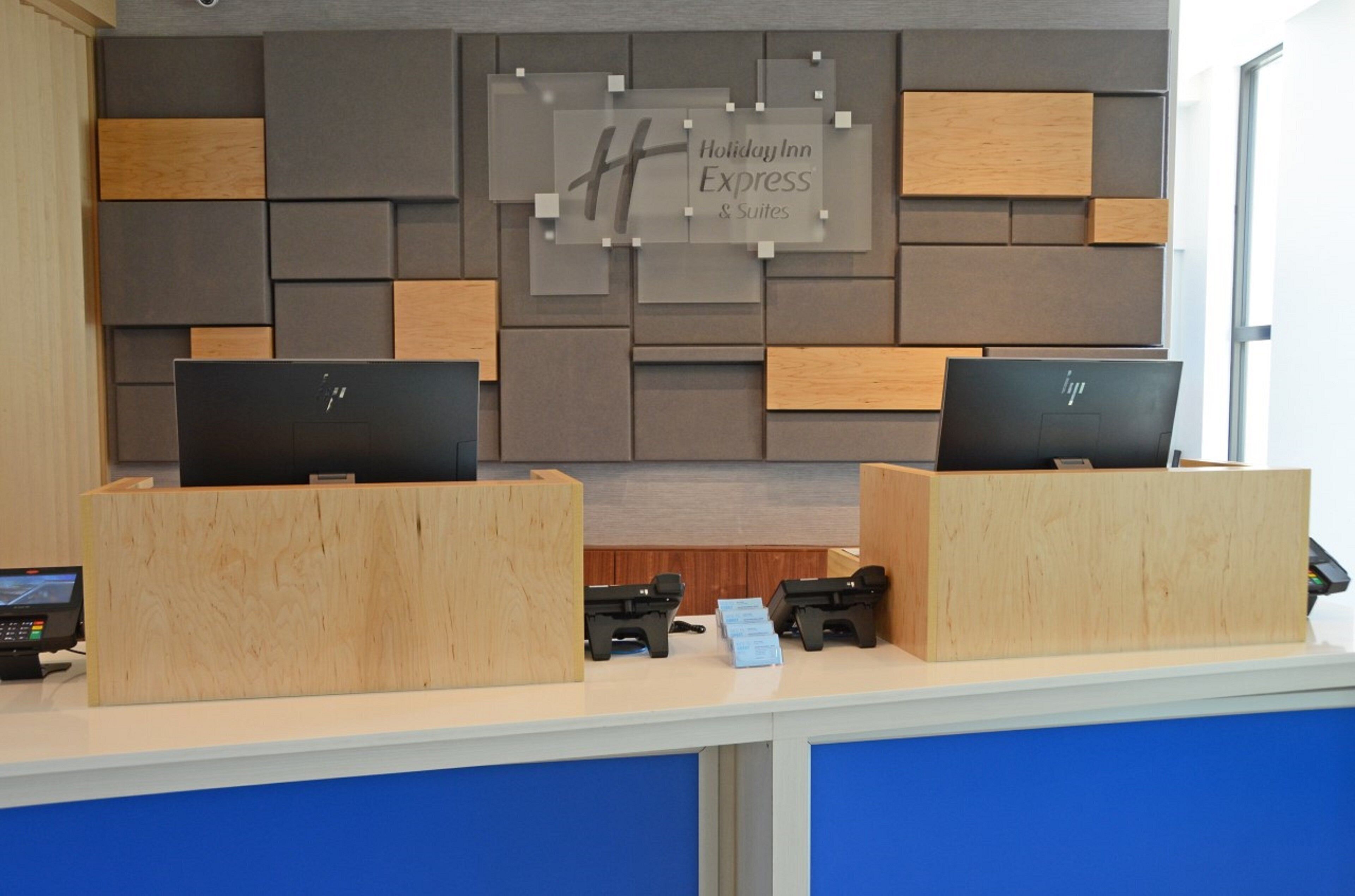 Een receptiebalie met twee HP computers, een Holiday Inn Express bord en een raam aan de rechterkant.