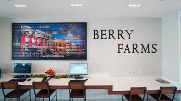 Un salón de conferencias con una larga mesa, cuatro sillas, dos monitores de computadora y un cuadro de gran formato con una vista panorámica de la ciudad.