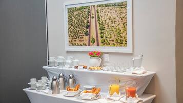 A breakfast buffet with coffee, tea, pastries, and juice.