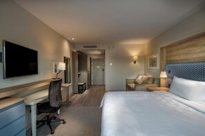 A hotel room with a bed, desk, chair, and a television.
