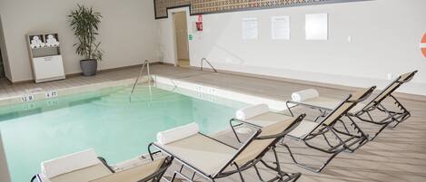 A swimming pool with lounge chairs and a potted plant.
