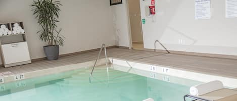 A swimming pool with lounge chairs and a potted plant.