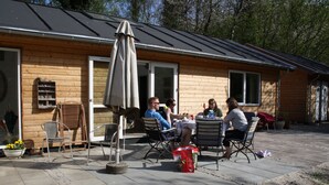A wooden cabin with a patio area, outdoor seating, and potted plants. - Penalhuzet (Ronne)