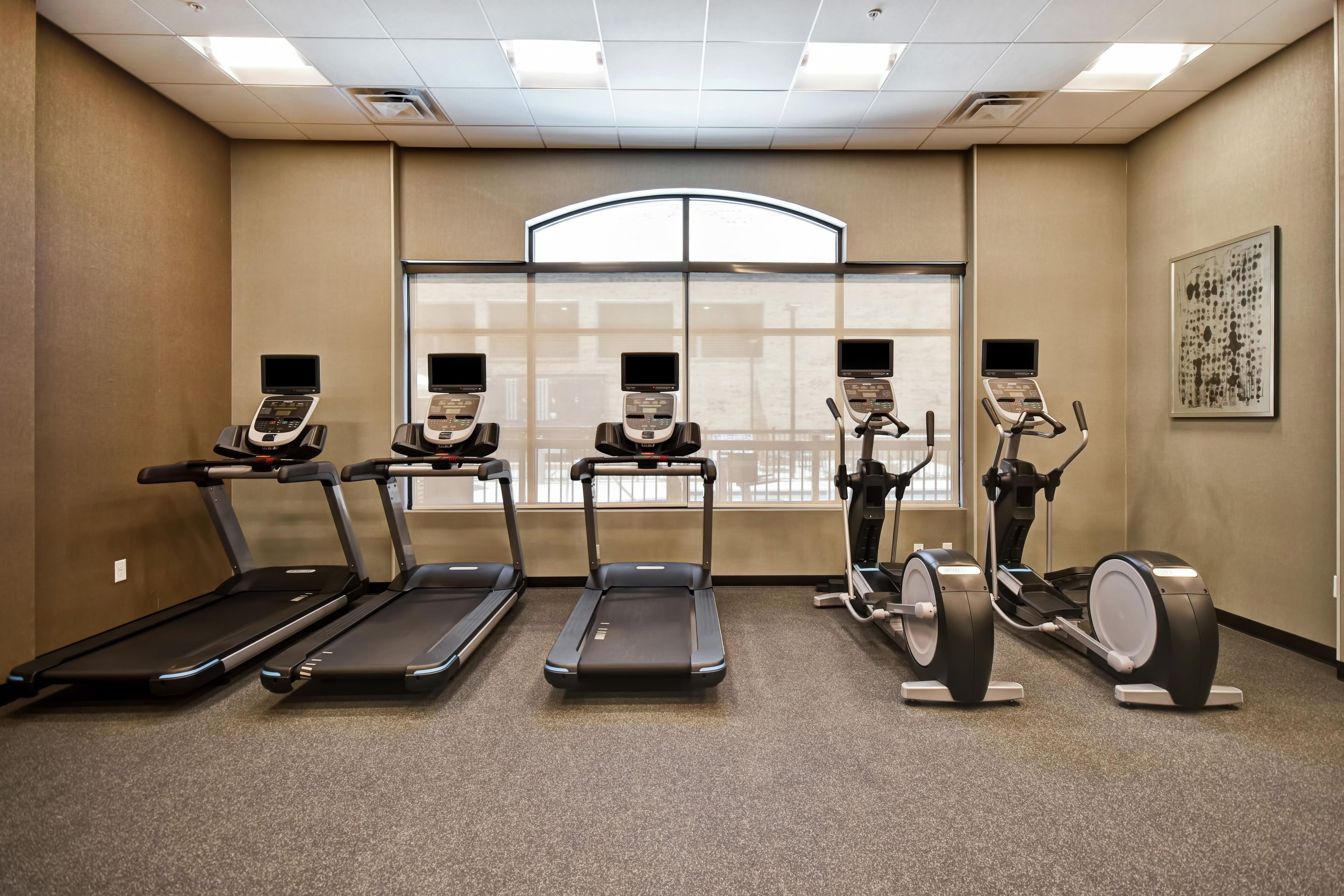 A fitness room with treadmills, elliptical machines, and a stationary bike.