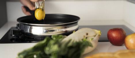 A hand cracking an egg into a frying pan on a stove.