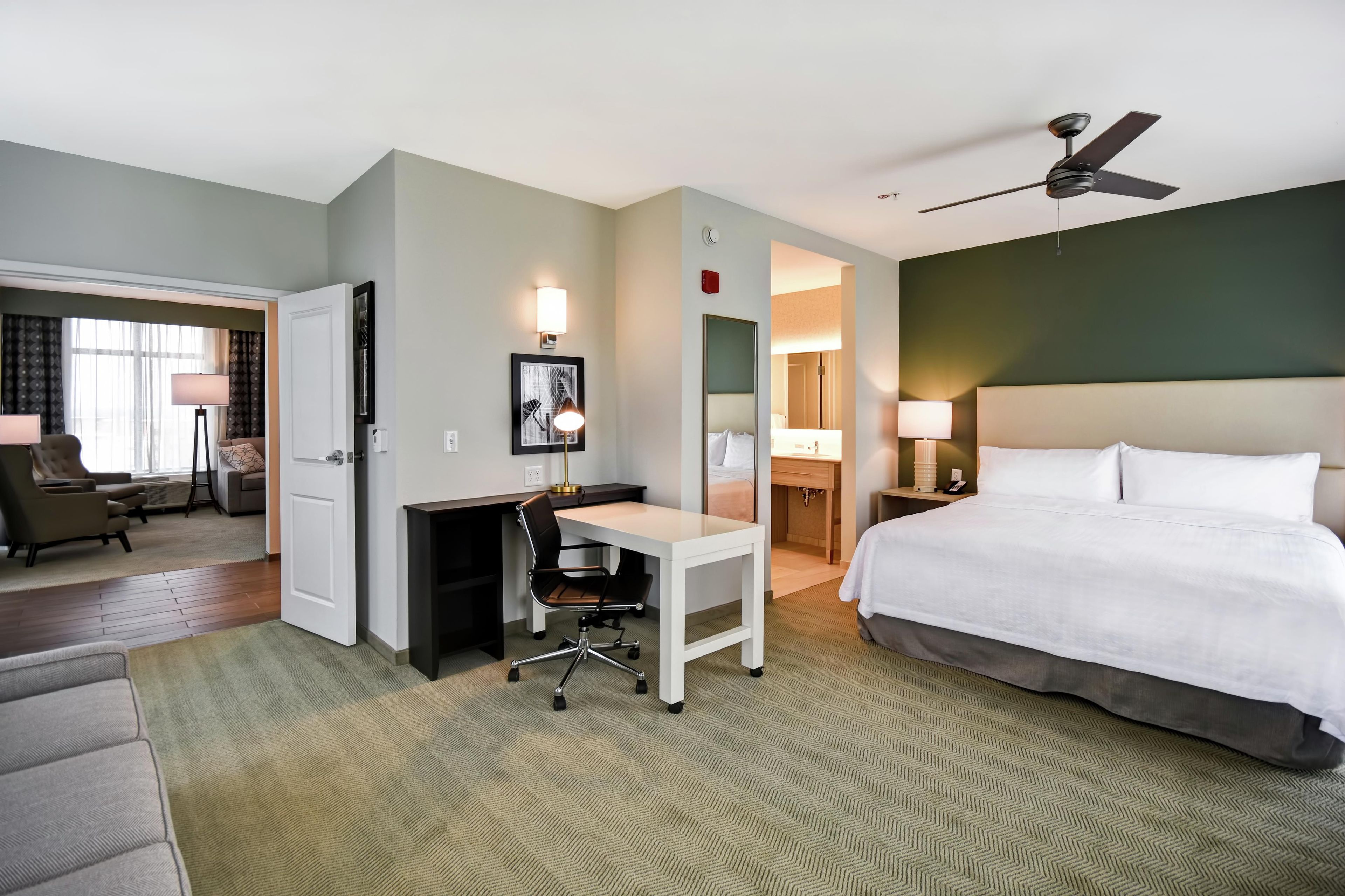 A hotel room with a bed, desk, chair, and a separate bathroom area.