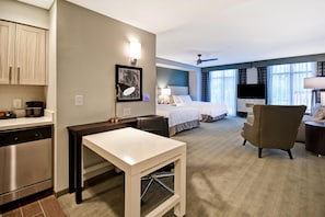 Hotellihuone, jossa on pieni keittiö, sänky, työpöytä ja tuoli.