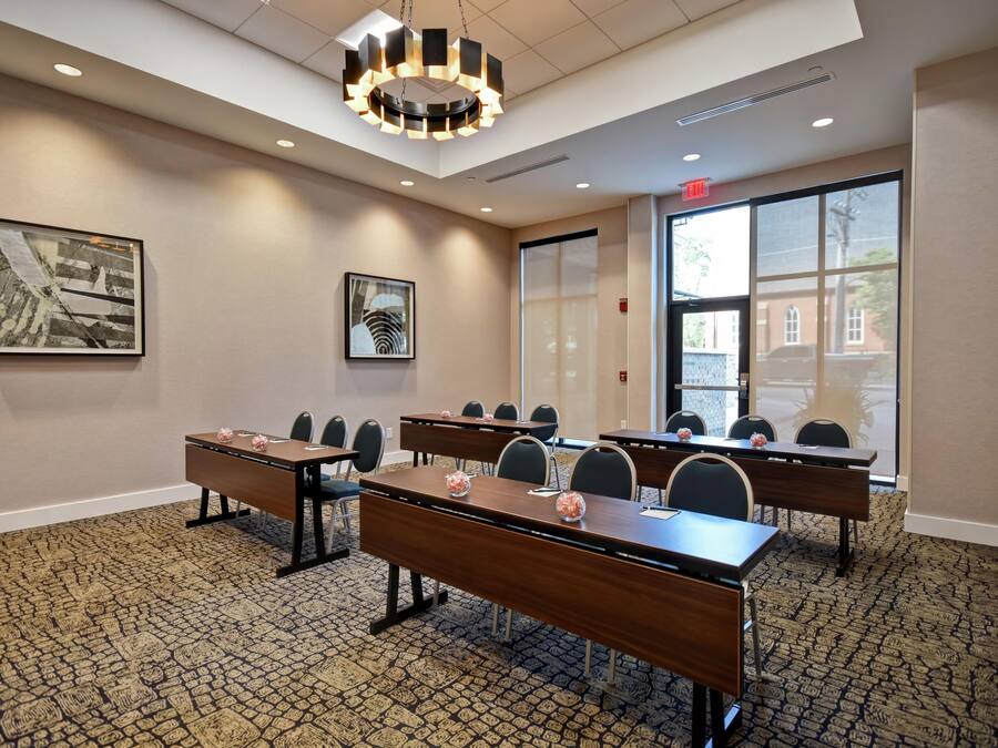 A conference room with multiple tables, chairs, and a large window providing a view of the outside.