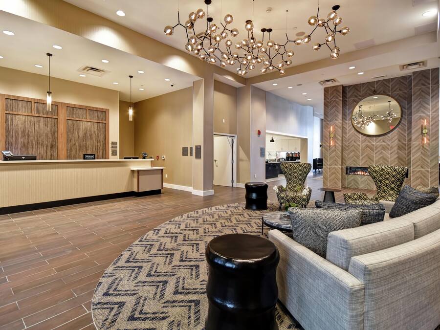 A modern hotel lobby with a reception desk, seating area, and a fireplace.