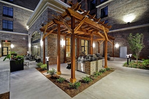 Ein Außenbereich mit Terrasse, einer Holz-Pergola, einem Grill und Sitzgelegenheiten.