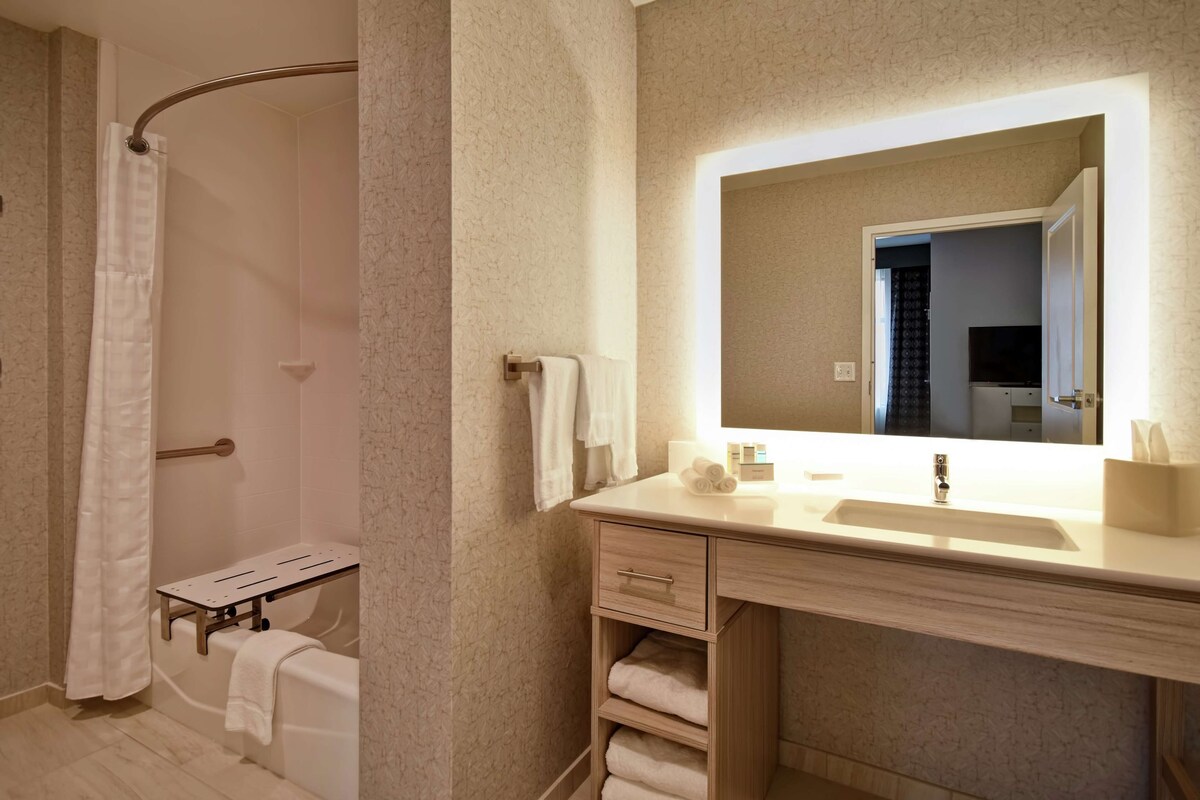 A bathroom with a shower, a sink with a mirror, and a towel rack.
