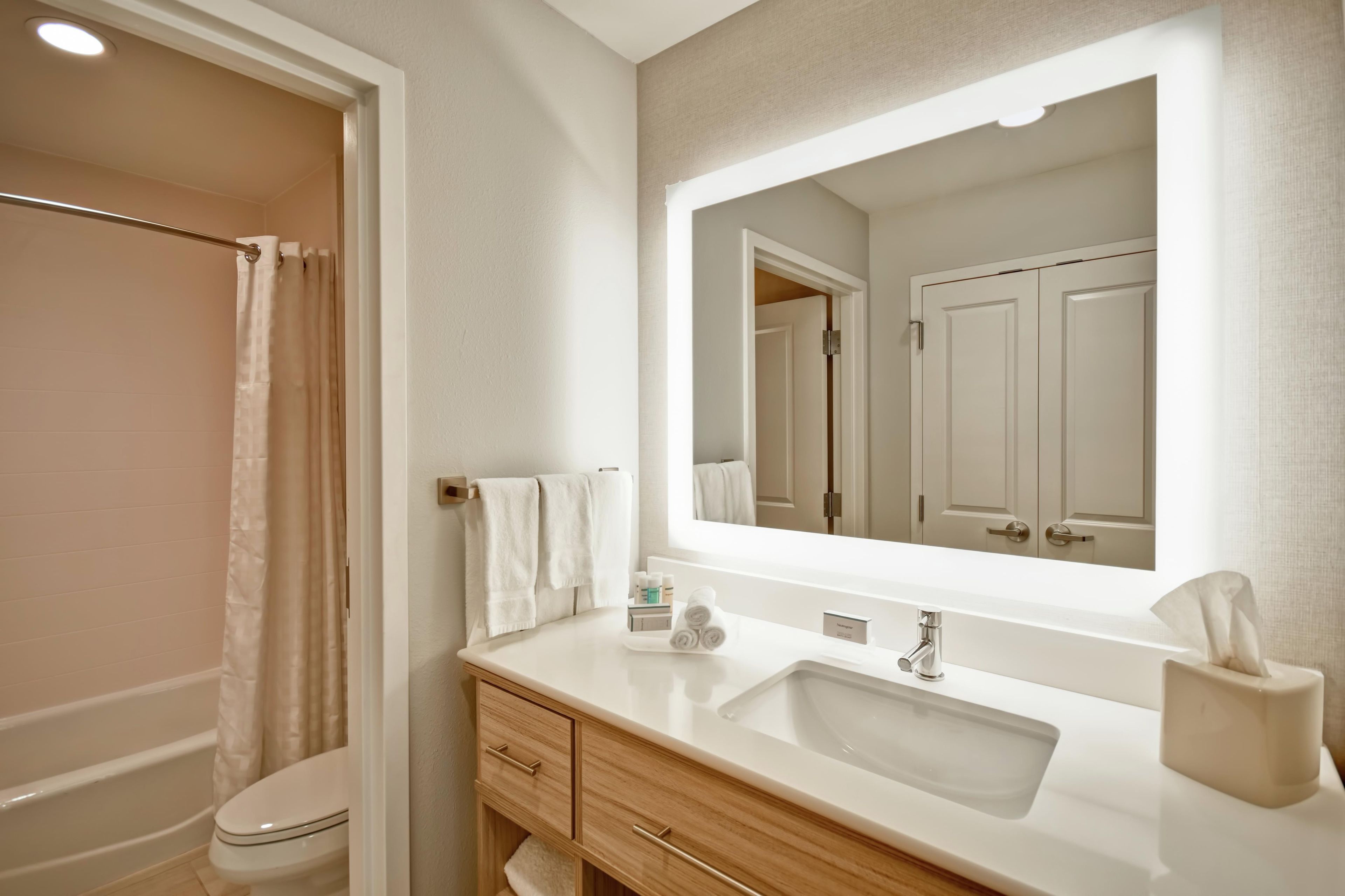 Un bagno moderno con doccia, servizi igienici, mobile lavabo e uno specchio grande.