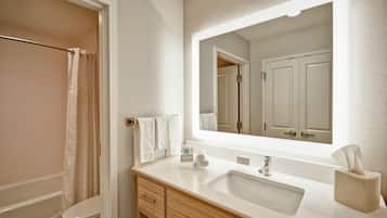 A modern bathroom with a shower, toilet, vanity with a sink, and a large mirror.