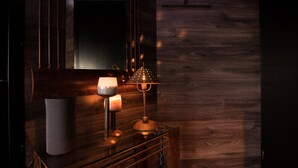 Un plancher en bois foncé, un miroir, une table avec une lampe et des bougies.