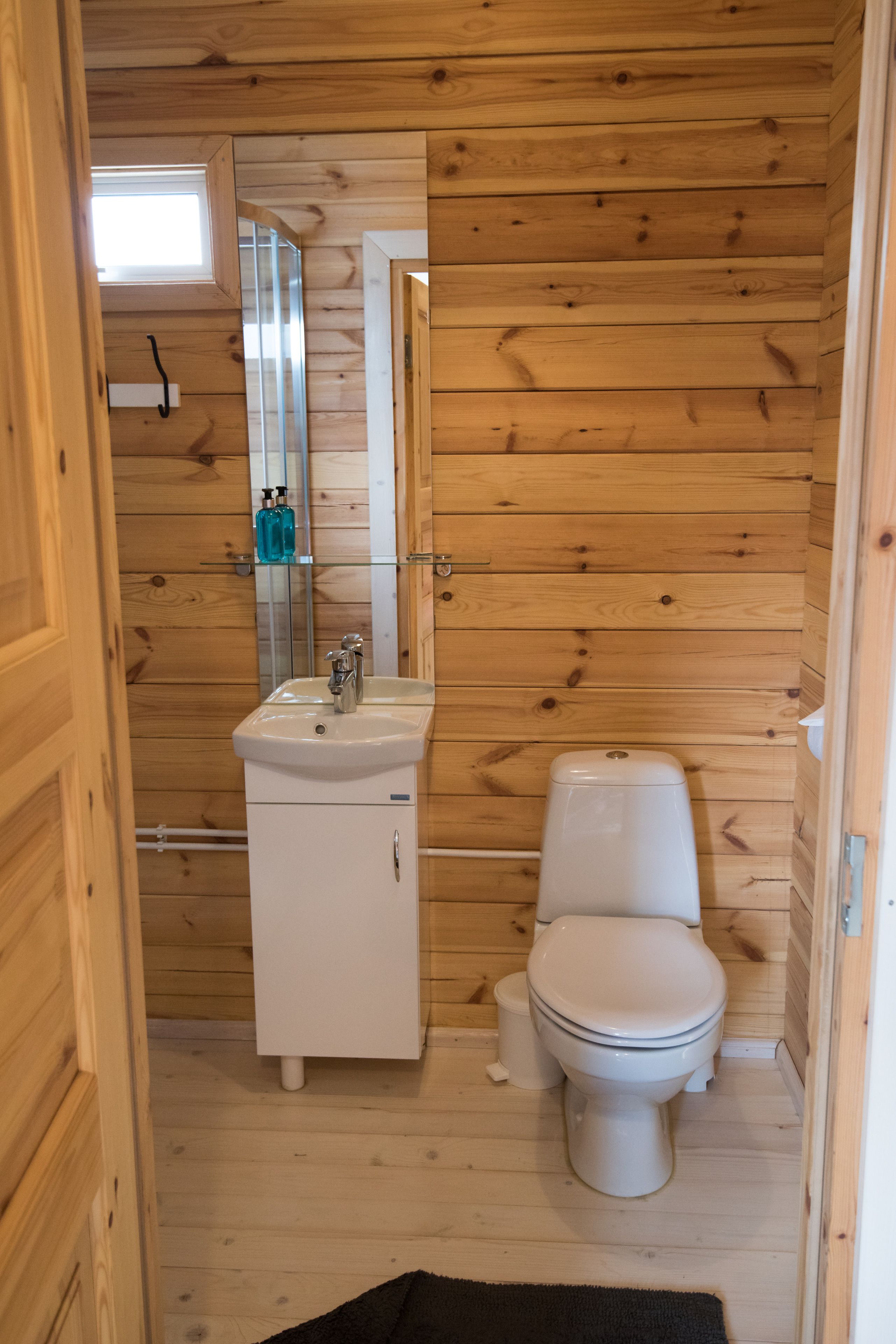 A wooden-paneled bathroom with a white sink, mirror, and toilet.