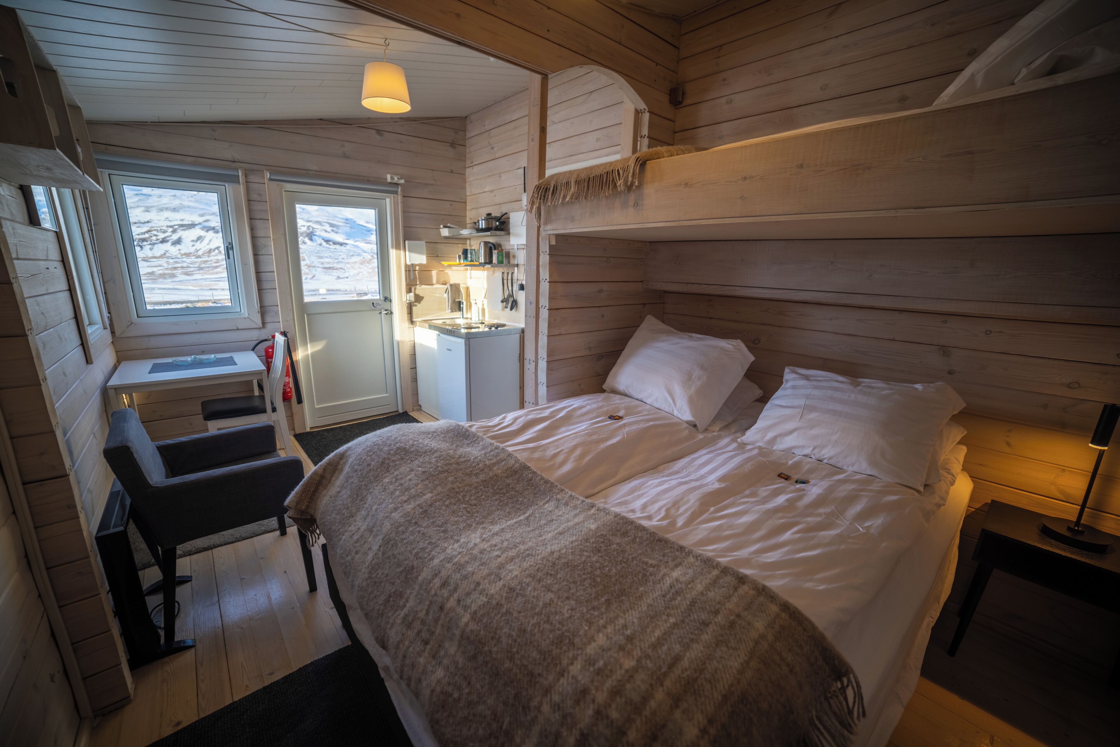 Accogliente camera da letto in una baita di legno con un letto a castello, una scrivania e un angolo cottura.