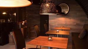 Un espace de salle à manger moderne avec une table et des chaises en bois, un luminaire suspendu original et un miroir au mur.