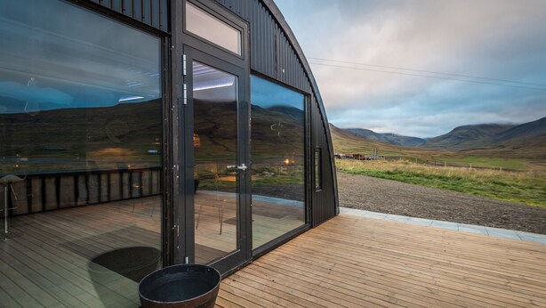 Un bâtiment moderne doté de grandes fenêtres en verre et d’une terrasse en bois.
