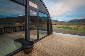 A modern building with large glass windows and a wooden deck. - Dalahyttur (Budardalur)