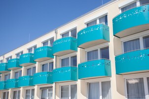 Una fila de balcones de hotel con un color turquesa uniforme y formas circulares.