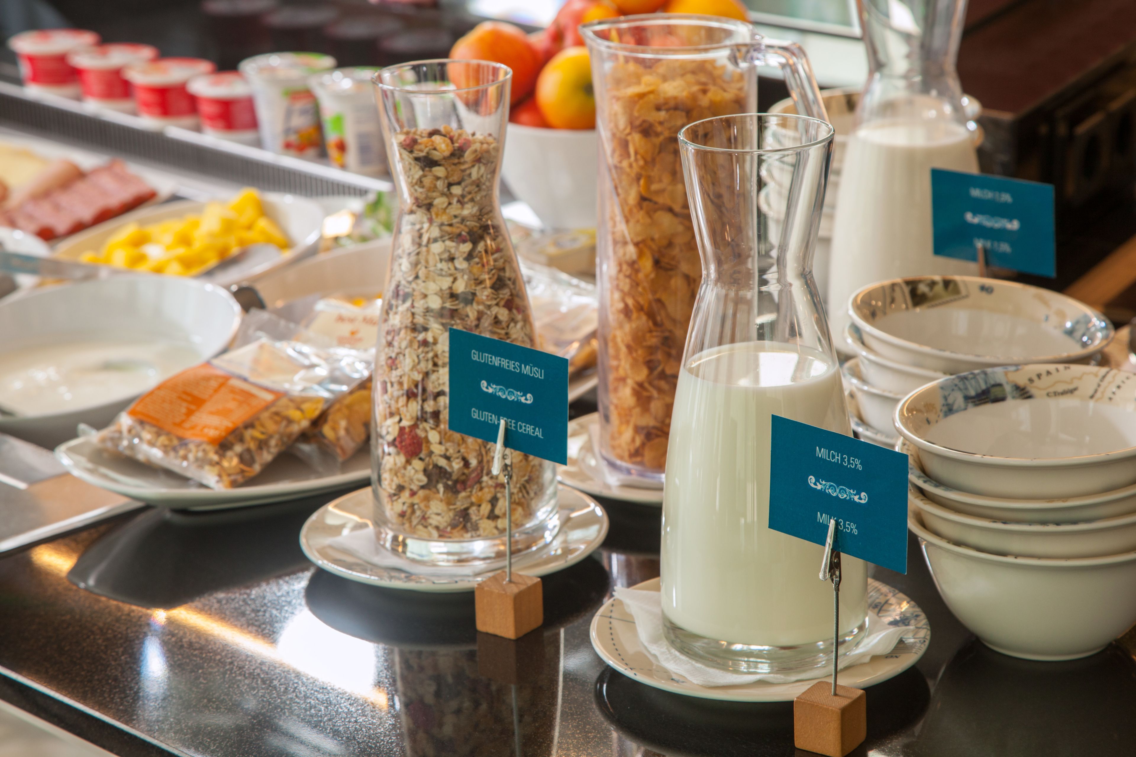 A buffet with various food items including cereal, milk, and fruits.