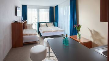 Una habitación de hotel con cama, escritorio, silla, mesita y televisor.