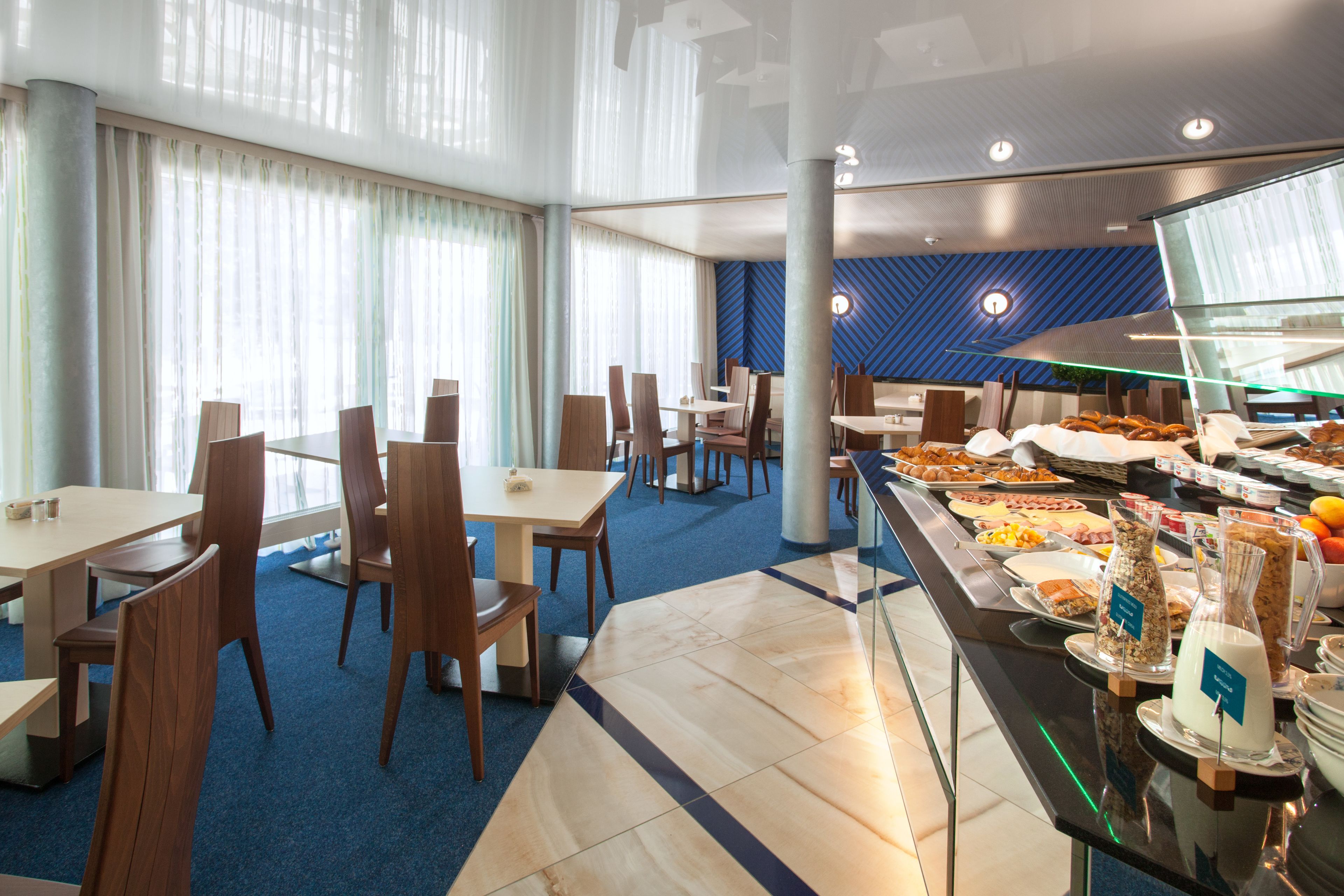 Zona de bufé con diversas opciones de comida, arreglos de asientos y un diseño interior moderno.