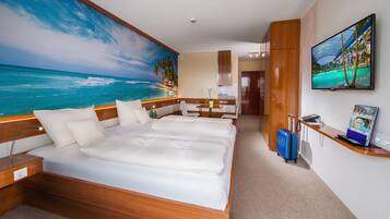 Quarto de hotel com uma cama grande, uma escrivaninha, uma cadeira, uma televisão e um quadro com uma cena de praia.