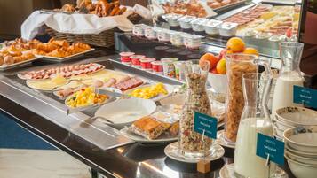 Un bufé con una variedad de alimentos, incluyendo pasteles, frutas y productos lácteos.