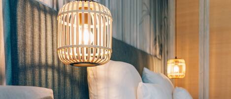 A hotel room with a bed, white pillows, and a hanging light fixture.