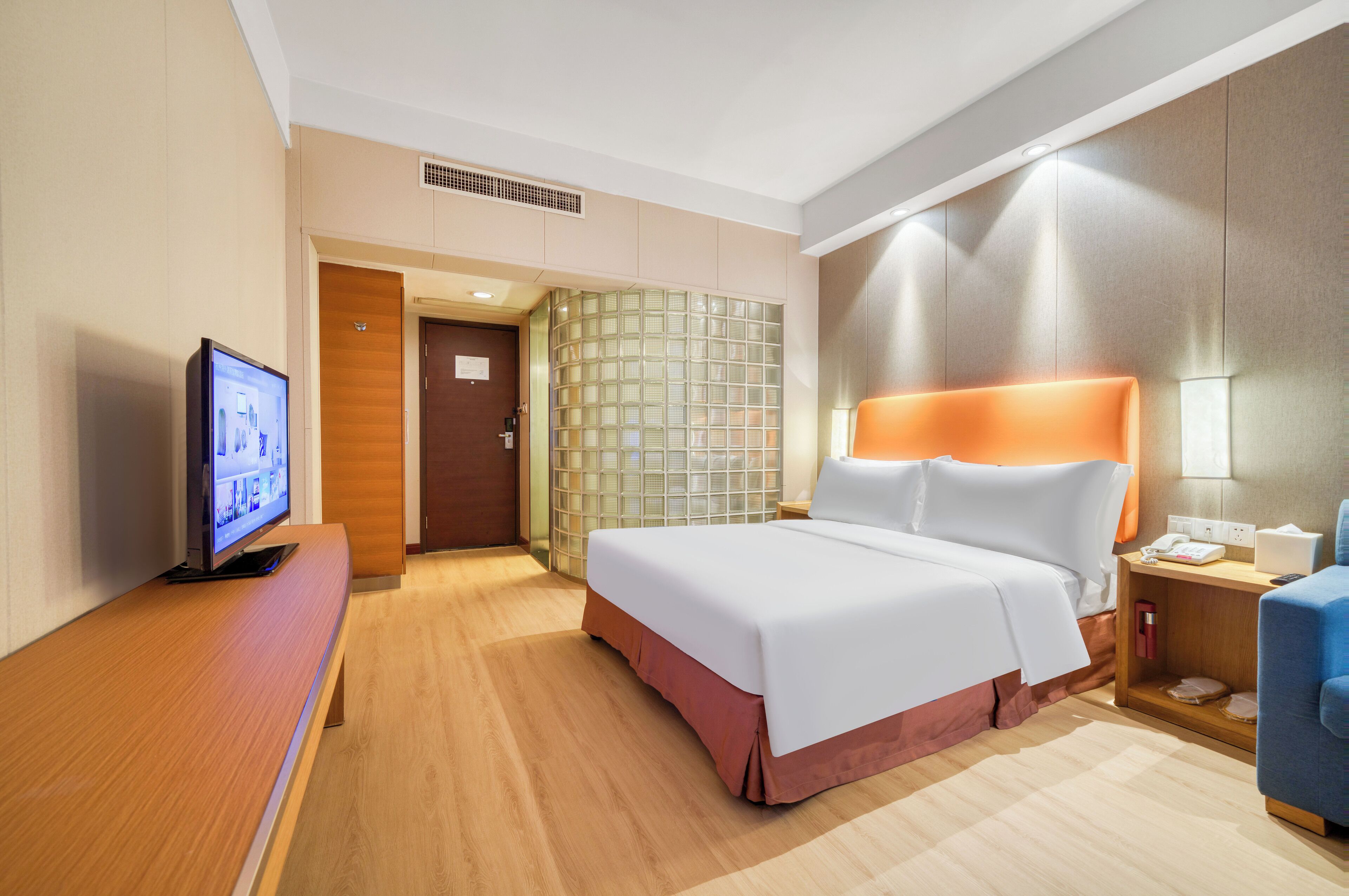 Ein Hotelzimmer mit Bett, Fernseher, Schreibtisch und Stuhl.