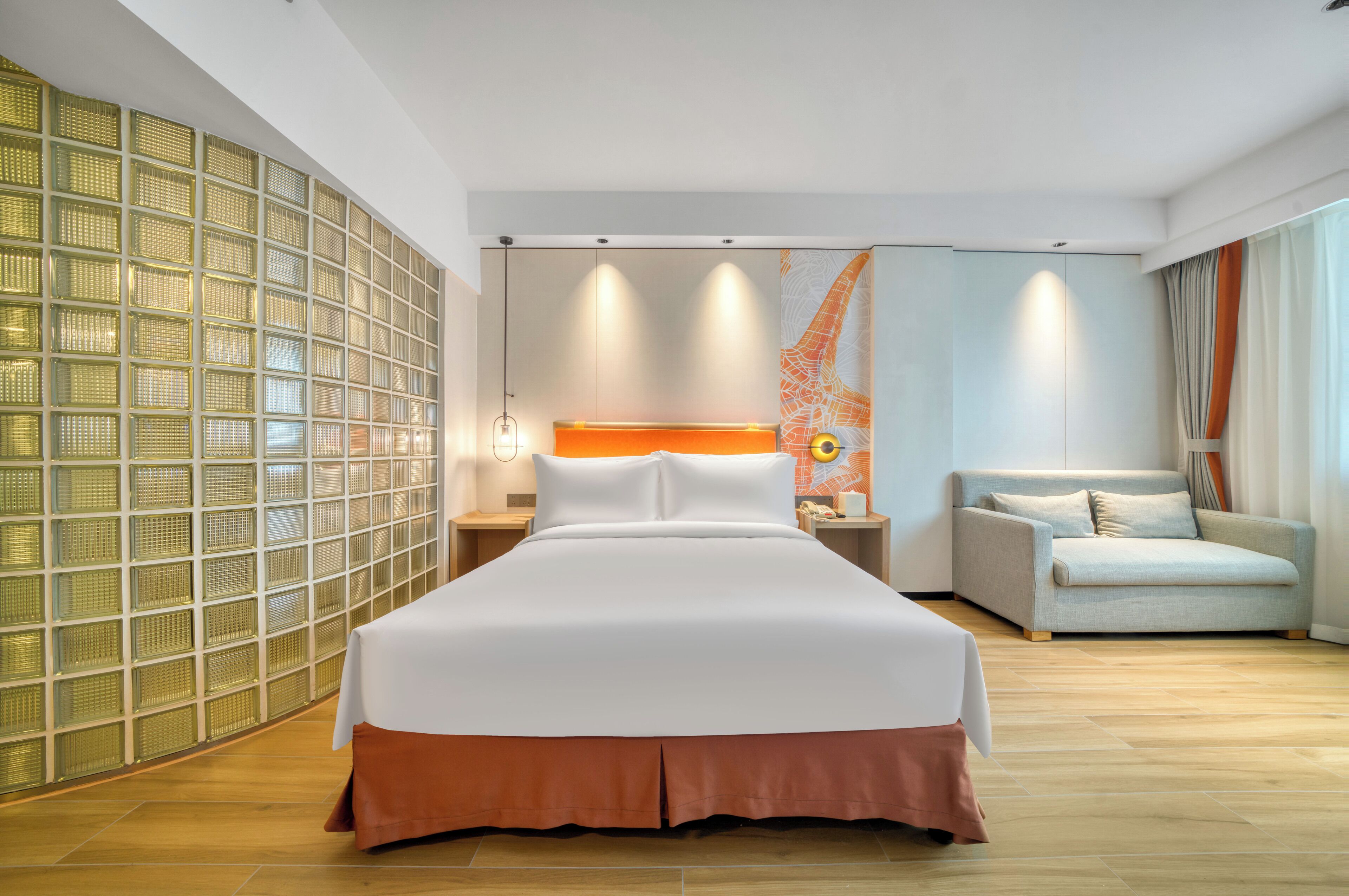 A hotel room with a large bed, a sofa, a wall with a geometric pattern, and a map artwork.