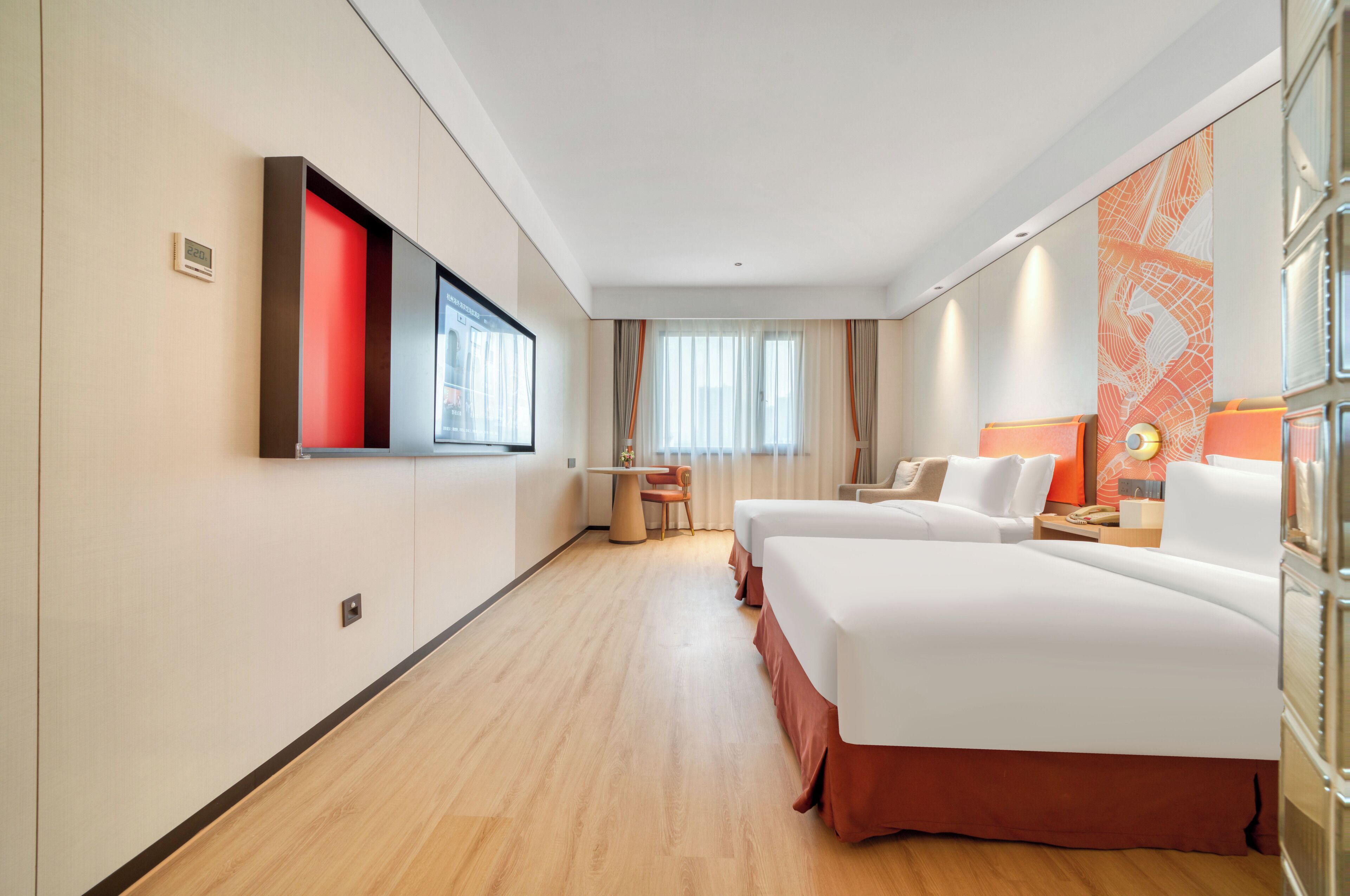 Habitación de hotel con dos camas, un escritorio, una silla, un televisor y una ventana con cortinas.