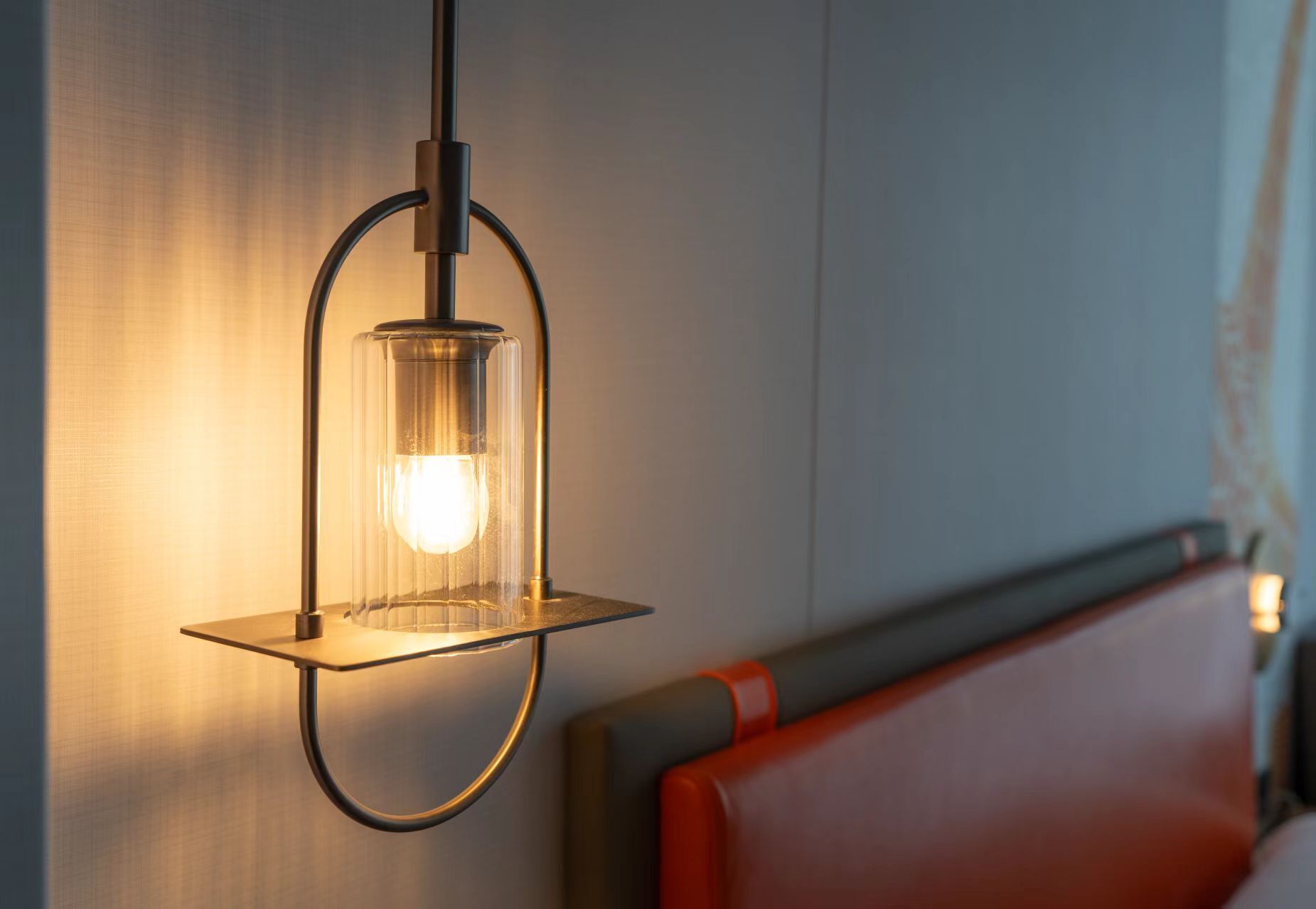 A modern interior with a hanging light fixture and a red upholstered bench.