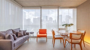 A modern living room with a sofa, a small round table, and two chairs. - Forma Itaim by Q Apartments (São Paulo)