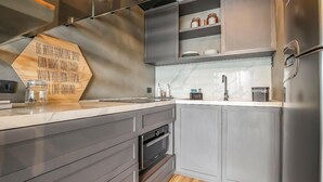 A modern kitchen with grey cabinetry, a built-in oven, and a wooden sign on the countertop. - Forma Itaim by Q Apartments (São Paulo)