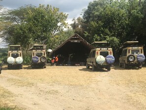 A safari lodge entrance with two safari vehicles parked in front. - Momella Wildlife Lodge (Arusha)