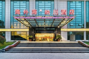 A hotel entrance with a glass canopy, steps leading up to it, and a sign above the entrance. - Hangzhou Haiwaihai Nachuan Hotel (Hangzhou)