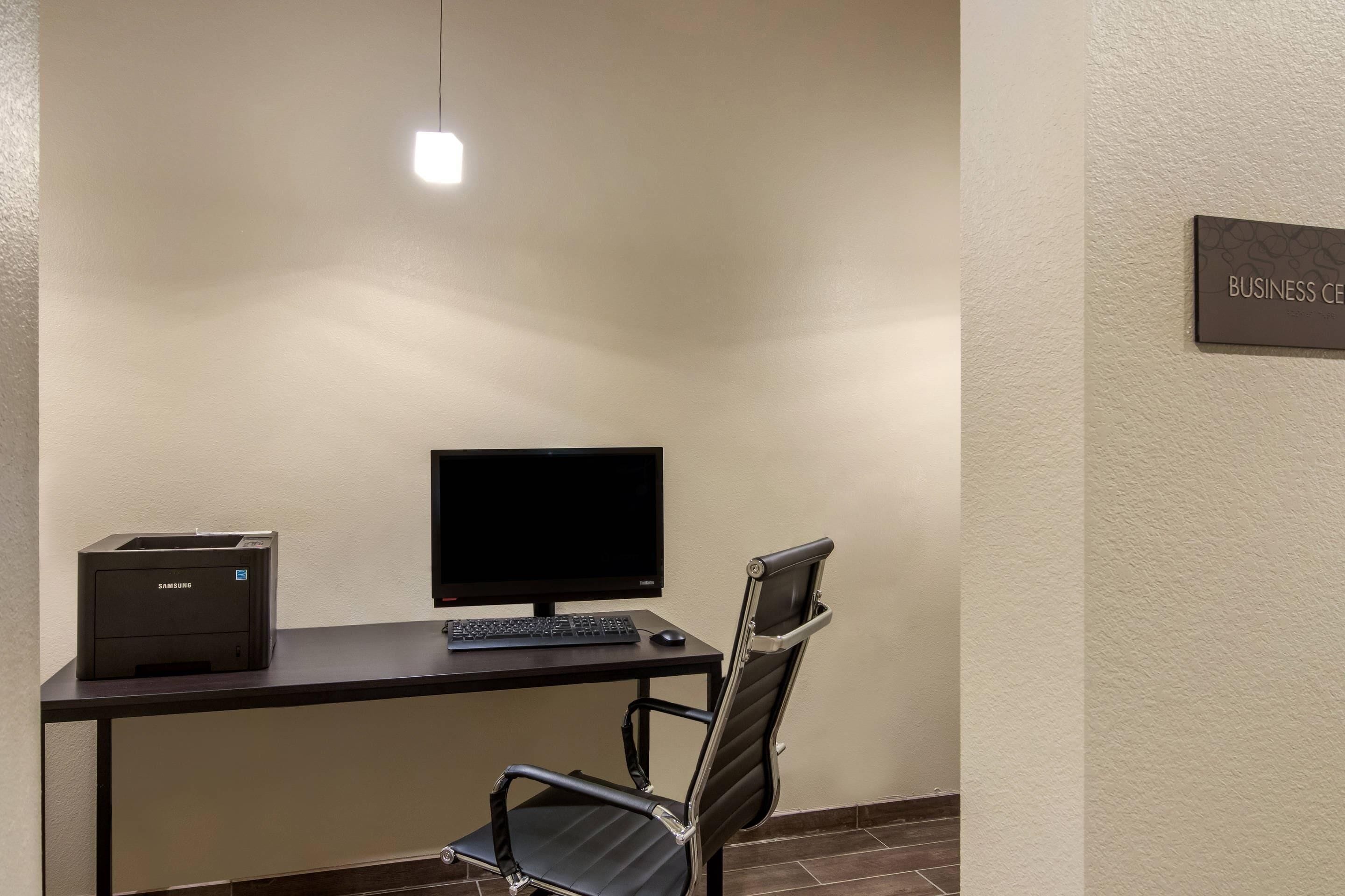 A workspace with a desk, a computer monitor, a keyboard, a chair, and a printer.