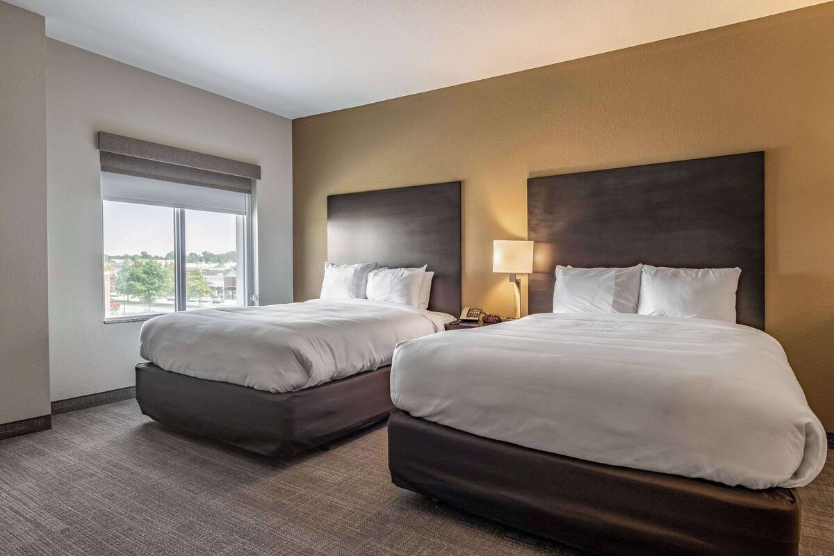 A hotel room with two beds, a large window, and a view of the city.