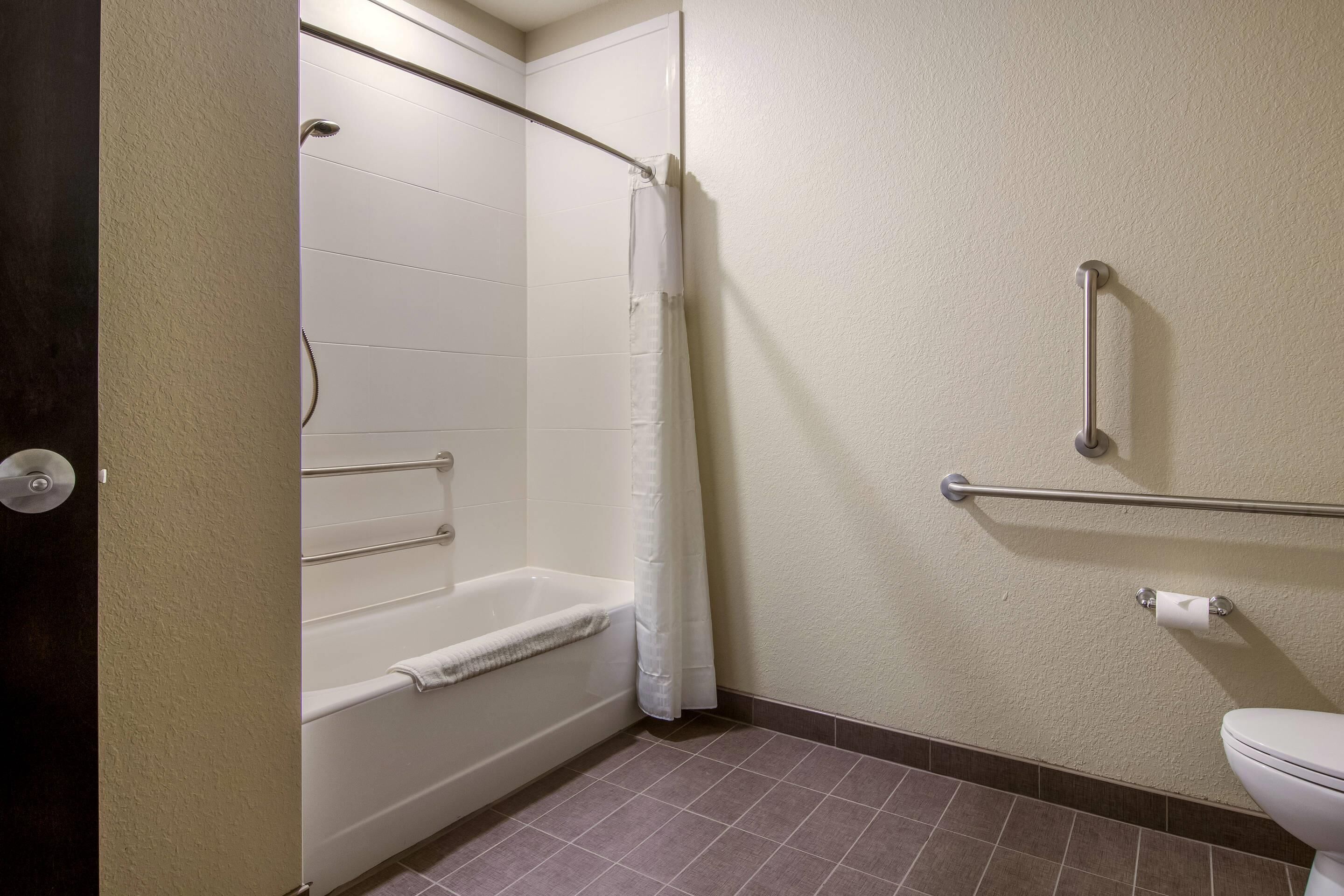 A bathroom with a bathtub, a toilet, and a shower curtain.