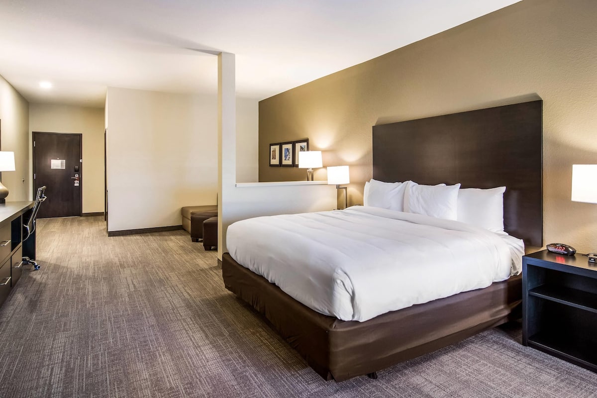 A hotel room with a large bed, bedside lamps, a desk, and a chair.