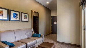 Un moderno vestíbulo de hotel con un sofá de cuero color beige, un reposapiés marrón y tres obras de arte enmarcadas en la pared.