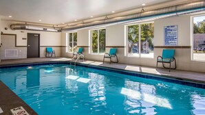 Una piscina interior con agua azul cristalina, un letrero que indica 'No saltar' y un cartel con las 'Normas de la piscina' en la pared.